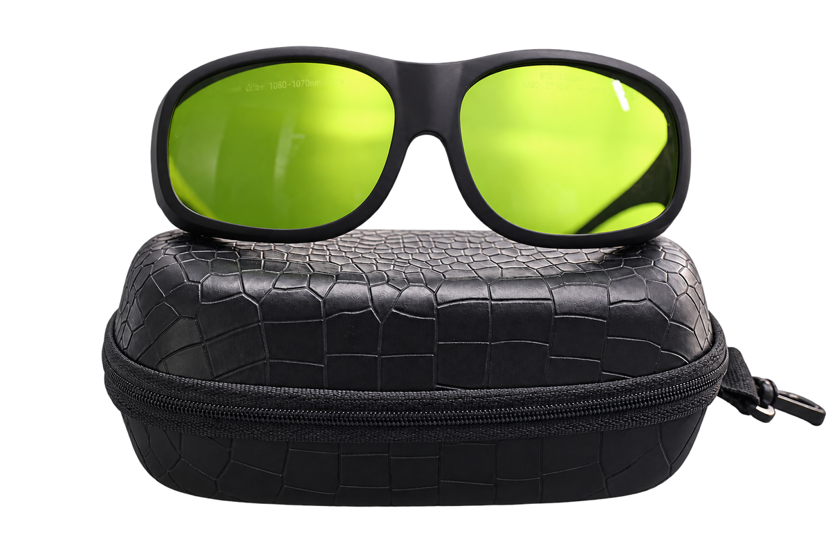 Front view of black wraparound laser safety glasses with yellow-green lenses resting on a black zippered case, isolated on a transparent background.
